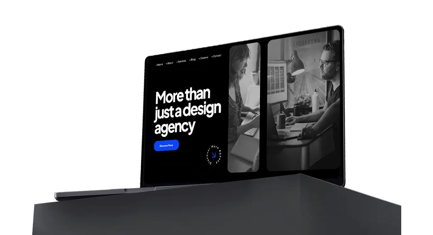 A laptop displaying a black-and-white website homepage with the headline "More than just a design agency" and a "Discover More" button